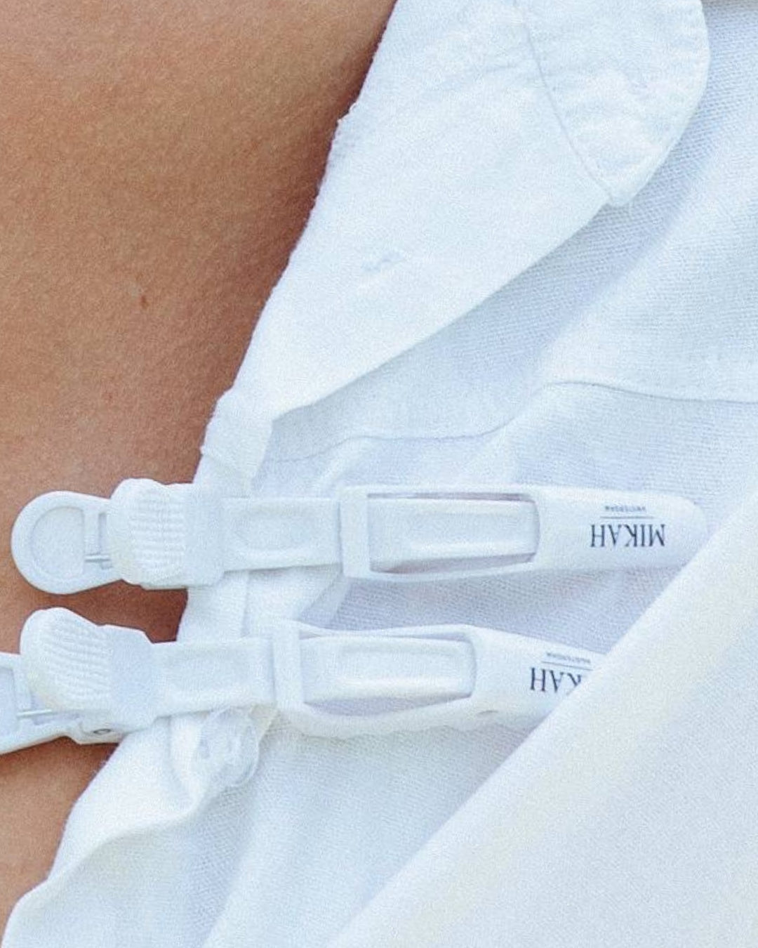 Close-up of Mikah Amsterdam hair clips attached to a white shirt, showcasing the brand’s logo.