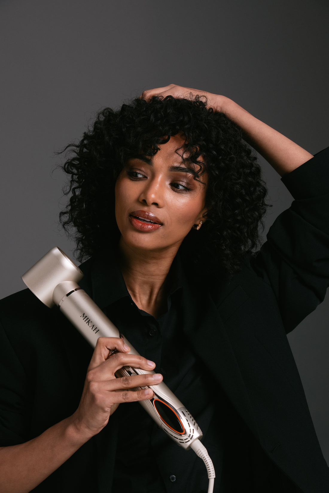 Woman using MIKAH 6-in-1 Air Styler to create curls and waves