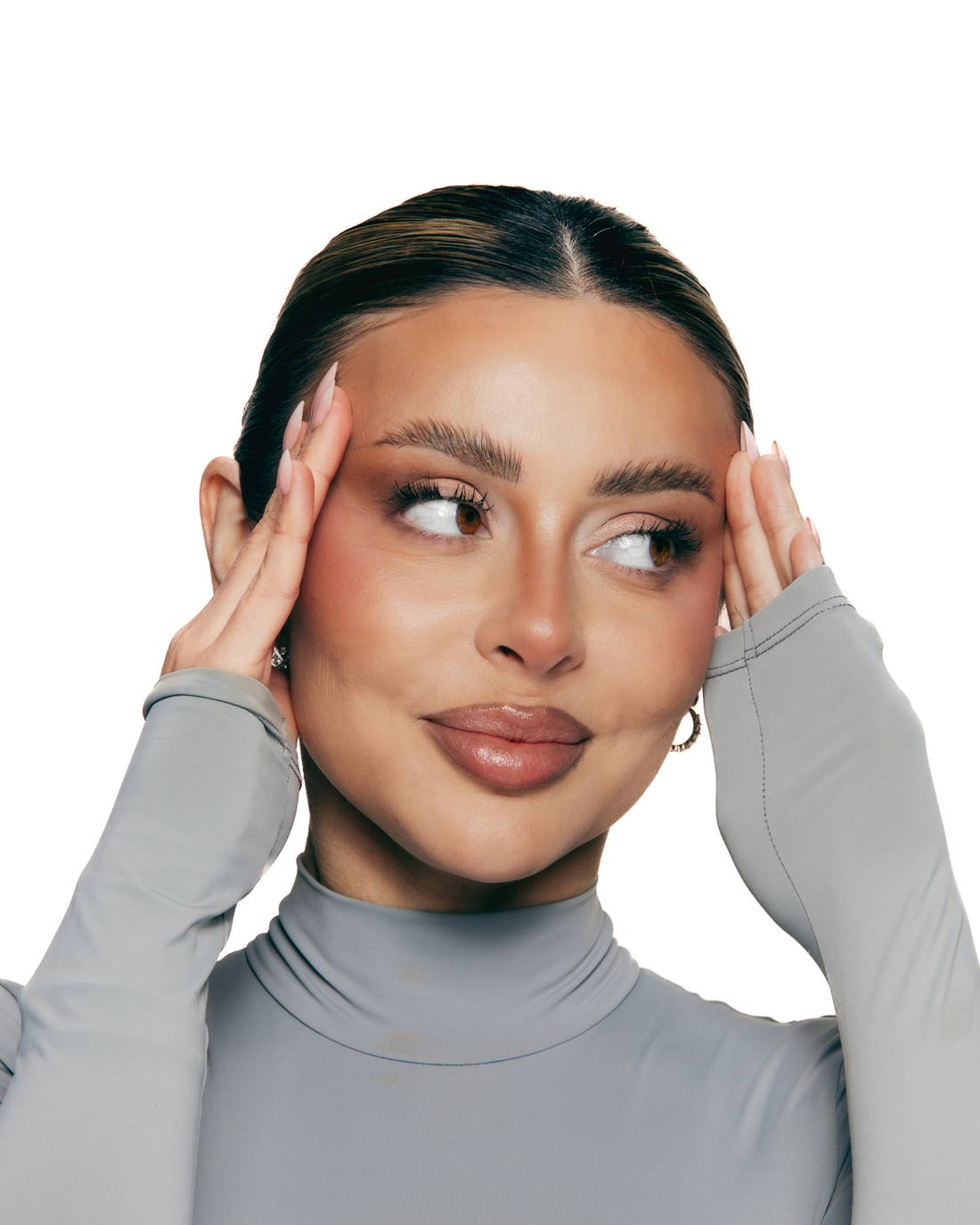 Woman with neatly styled and lifted eyebrows touching her face