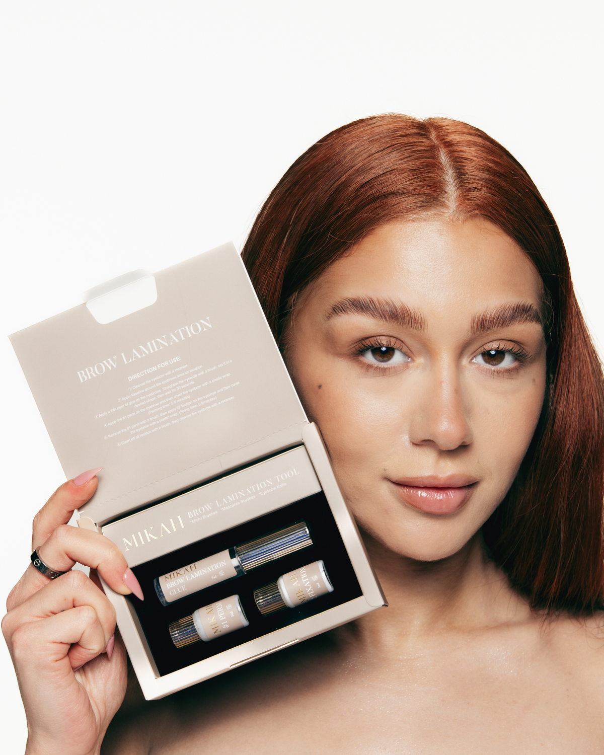 Woman holding an eyebrow lamination kit with treatment products and accessories