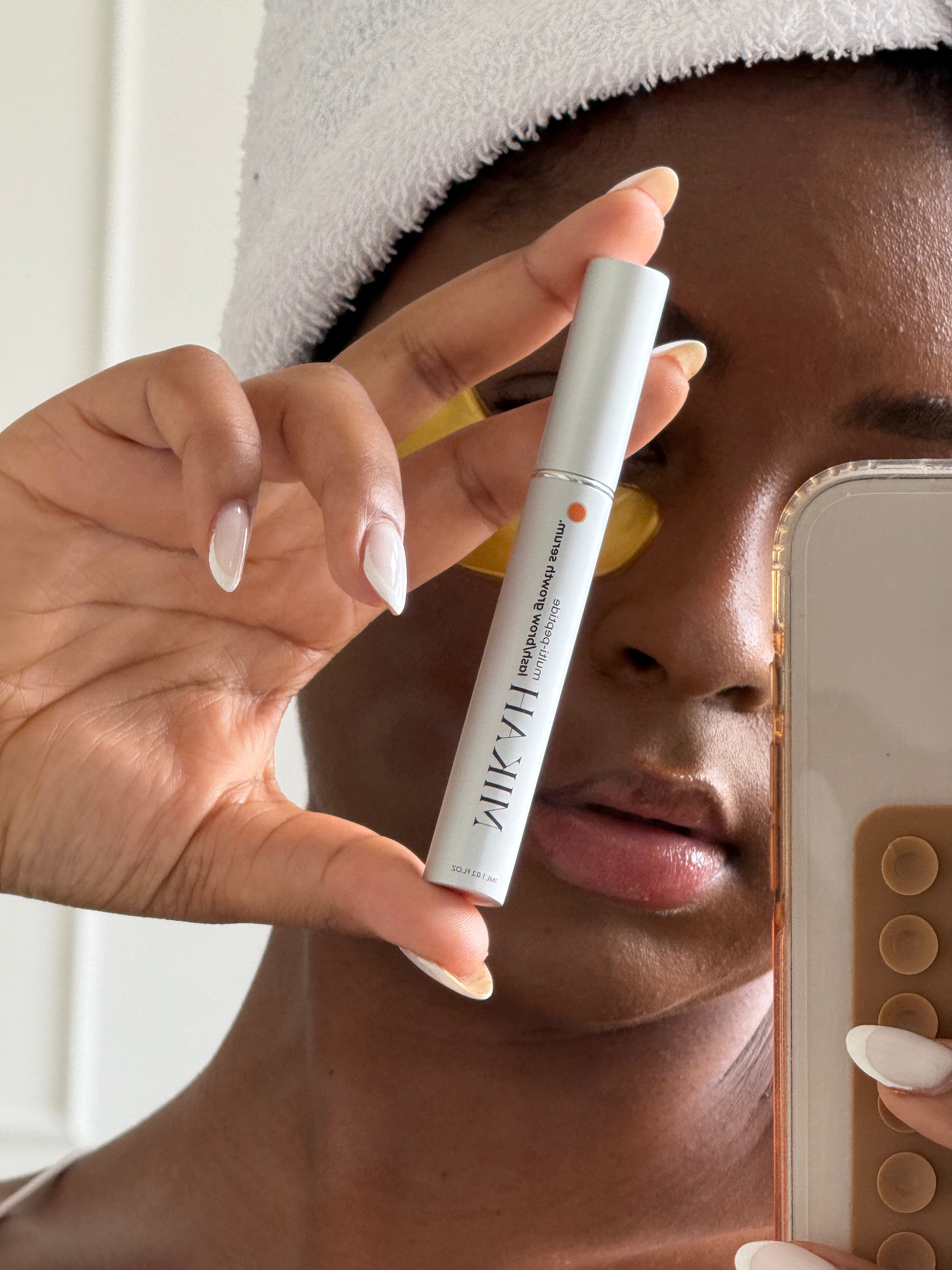Woman holding MIKAH Lash &amp; Brow Serum near her face