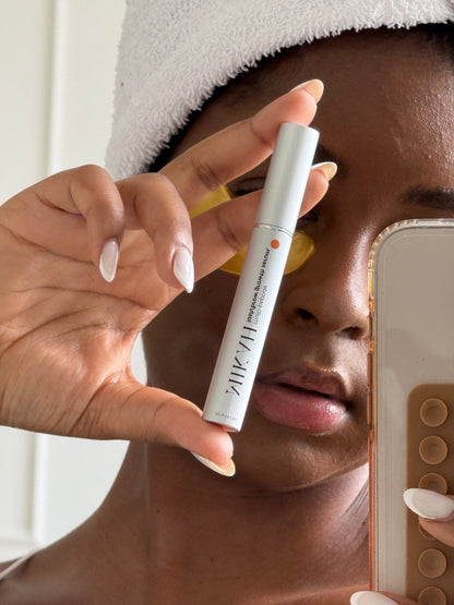 Woman holding MIKAH Lash &amp; Brow Serum near her face
