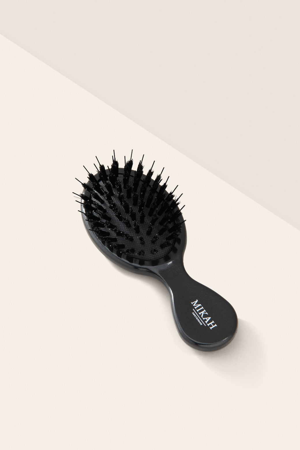 MIKAH black travel size detangling hairbrush showing nylon bristles